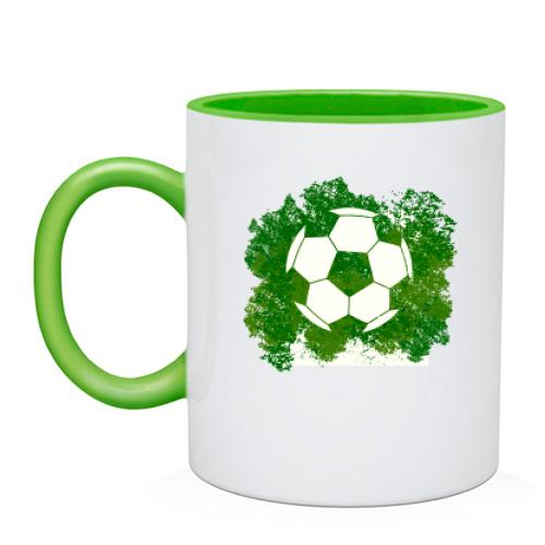 Чашка с футбольным мячом на фоне зелени