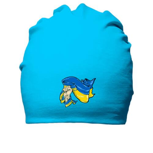 Хлопковая шапка з прапор України в руці
